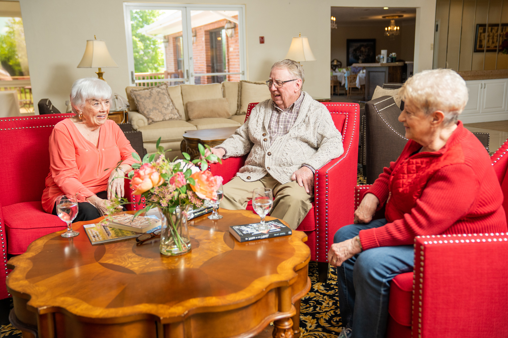 Seniors enjoying a lively conversation in a comfortable common area, highlighting the social environment in assisted living at Mari de Villa Senior Living.