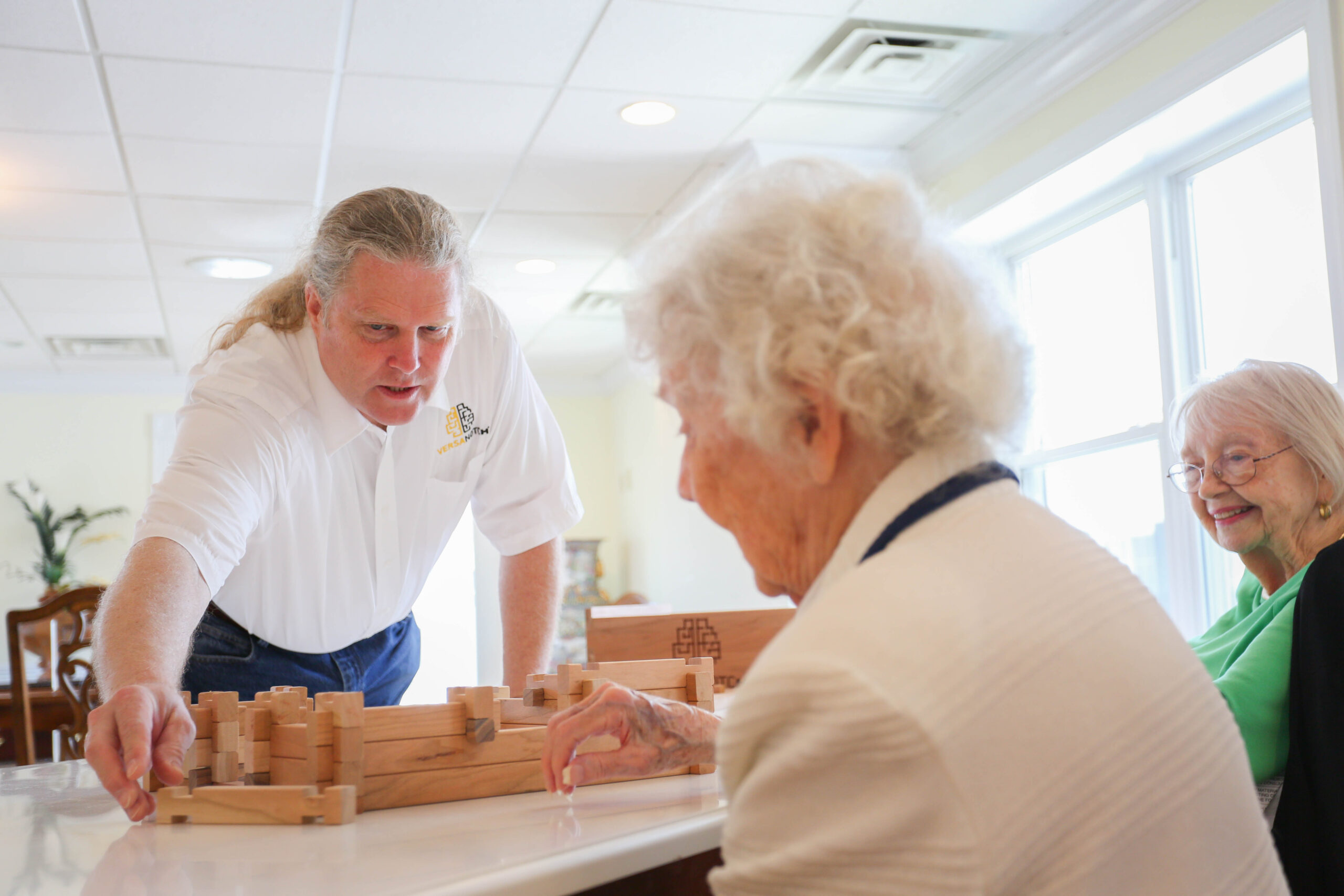A caregiver engaging with senior residents in cognitive therapy at Mari de Villa Senior Living.