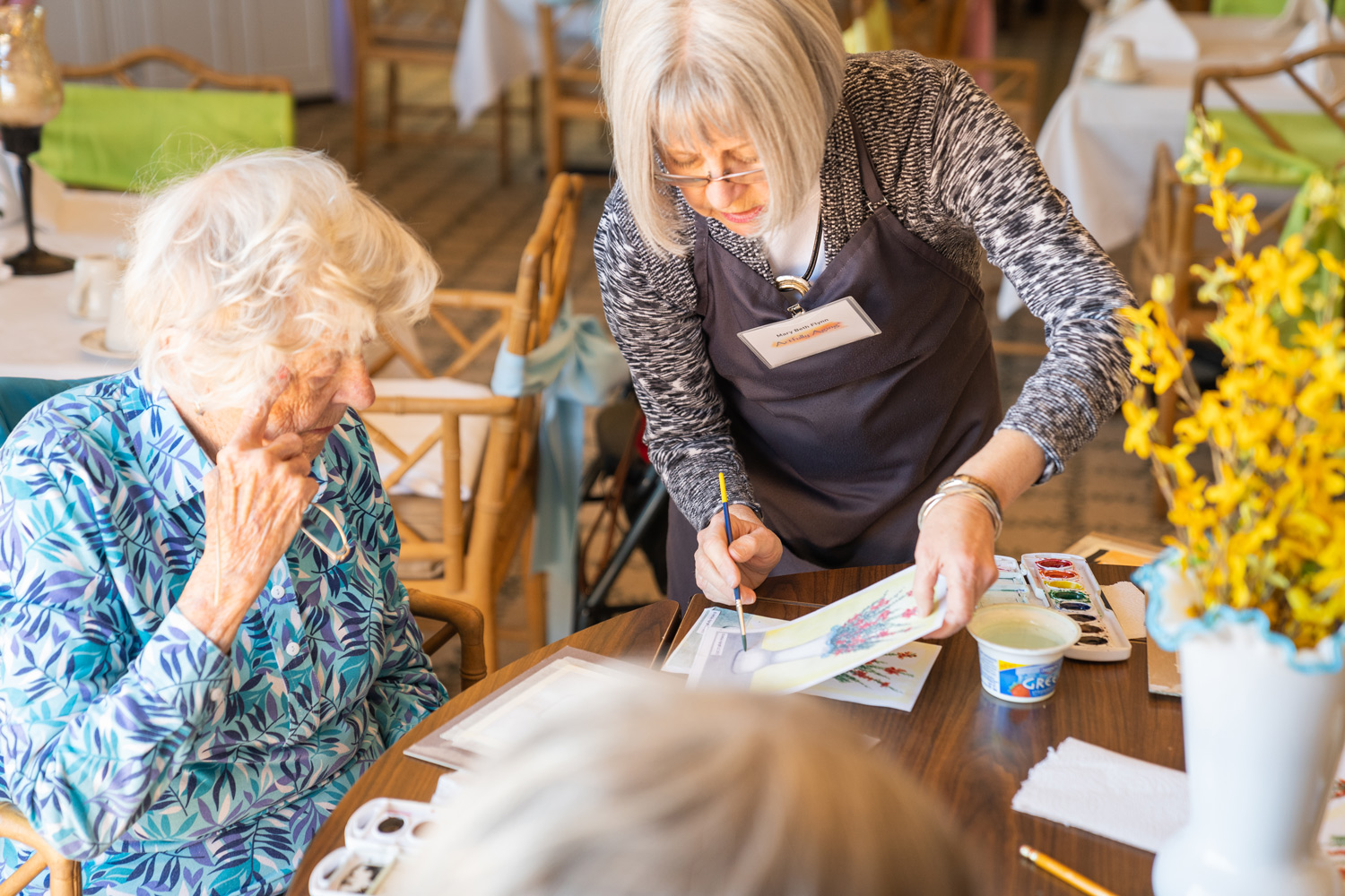 Caregiver assisting a resident with painting activities at Mari De Villa dementia care facilities.
