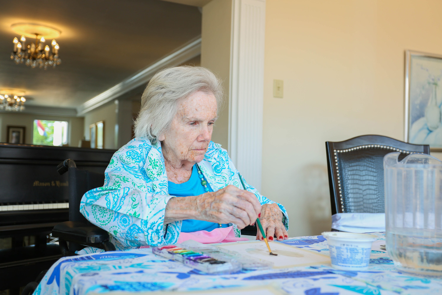 Senior resident participating in a memory care group activity, engaging with art at Mari de Villa.