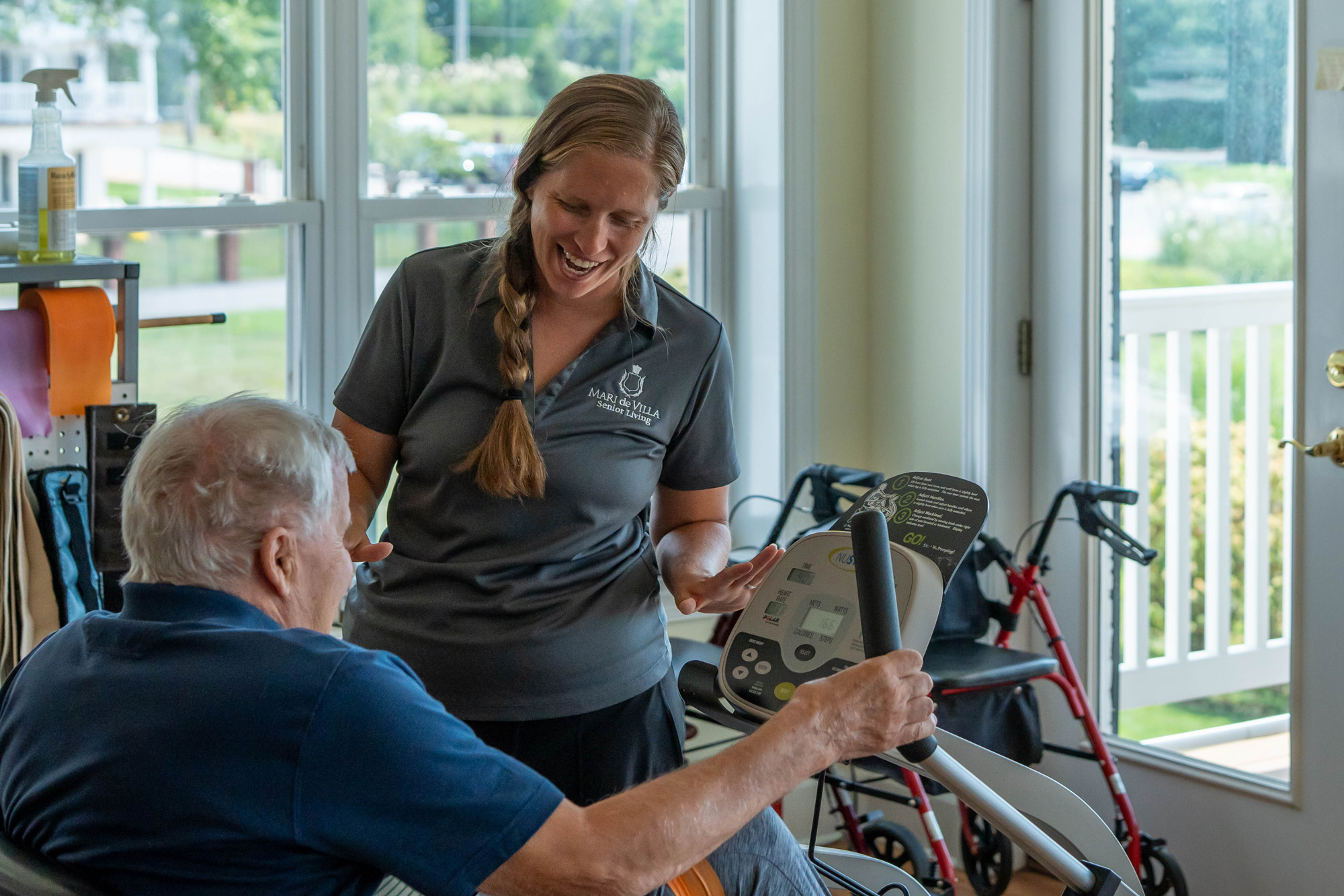 Senior resident exercising with caregiver supervision.