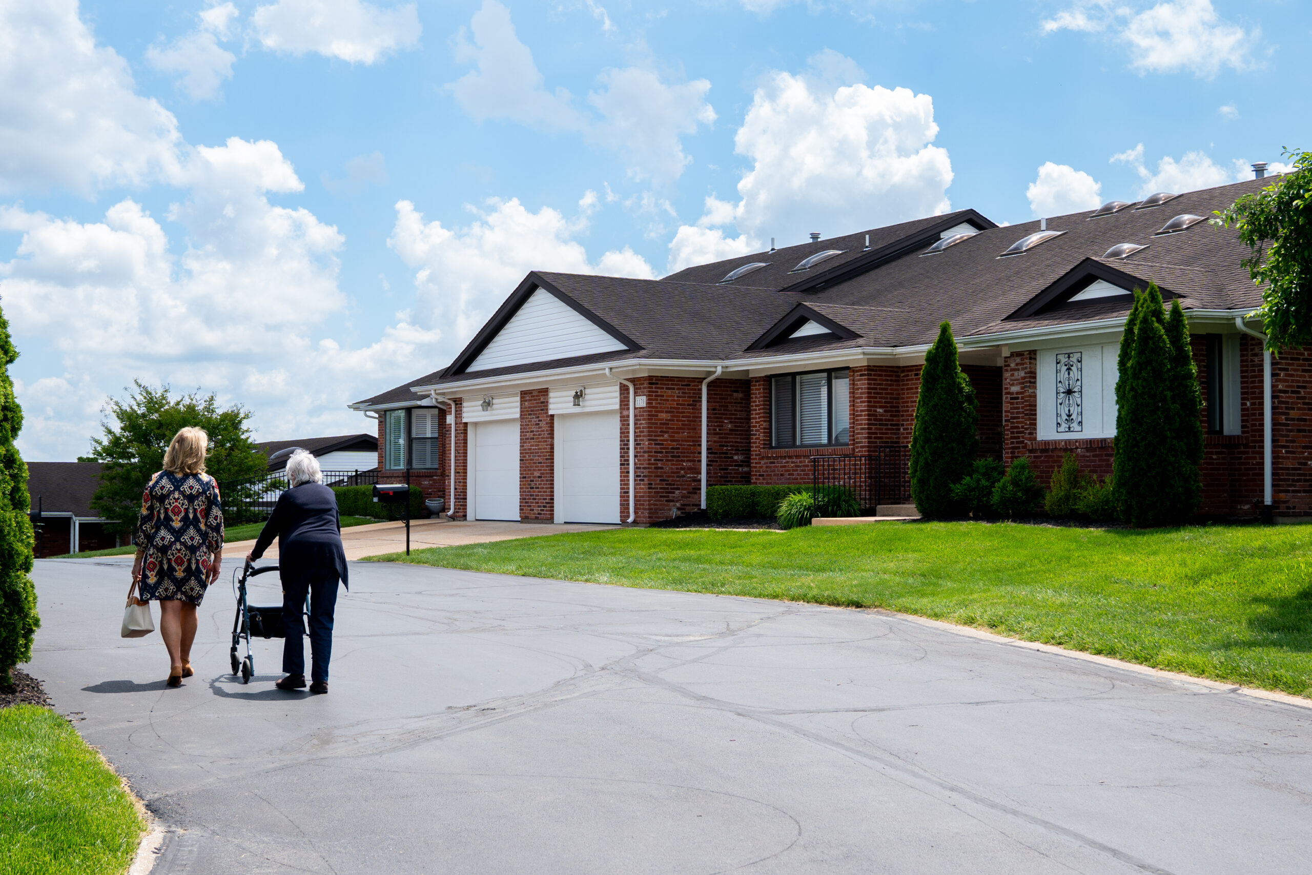 Elegant St. Louis senior living community with garden paths and residents walking