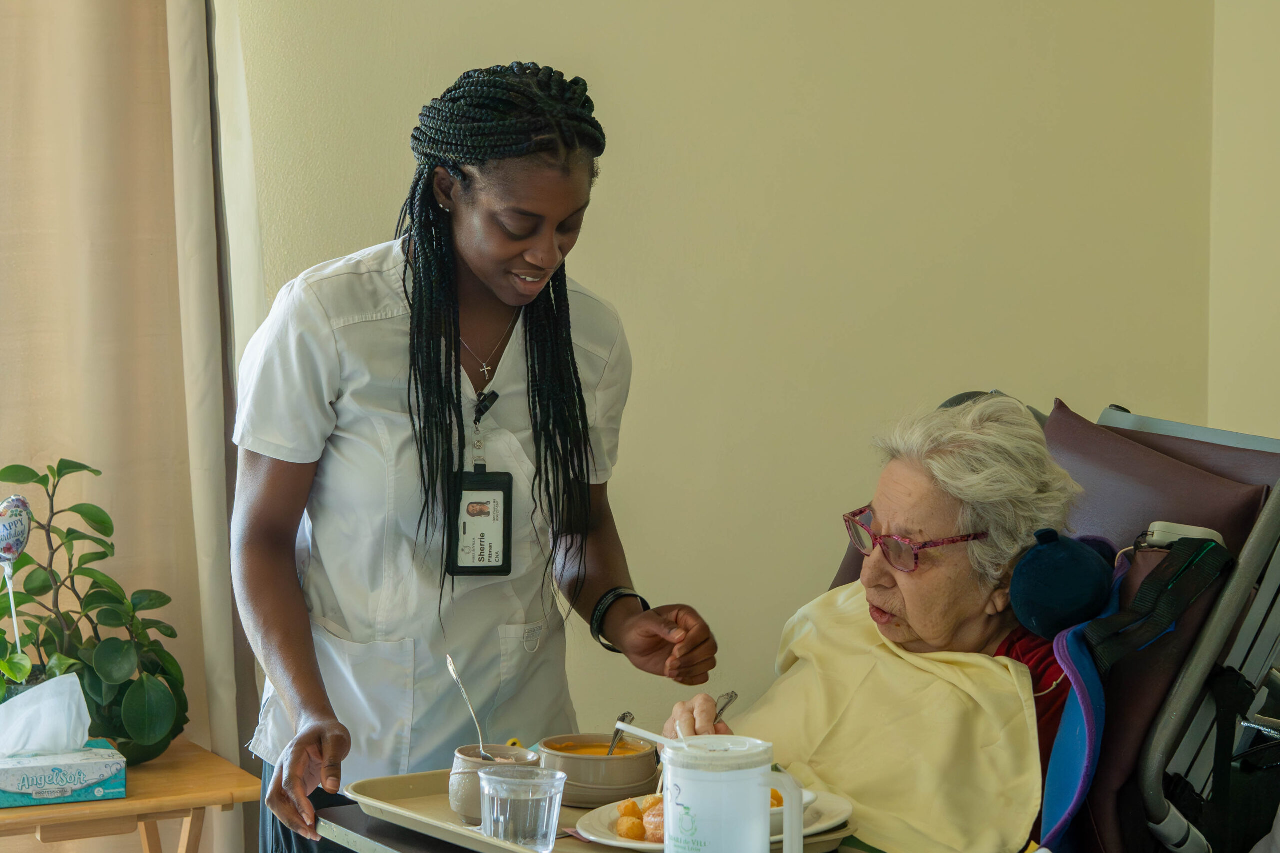 Resident receiving personalized care from a nurse in a warm, inviting suite at Mari de Villa senior living community.