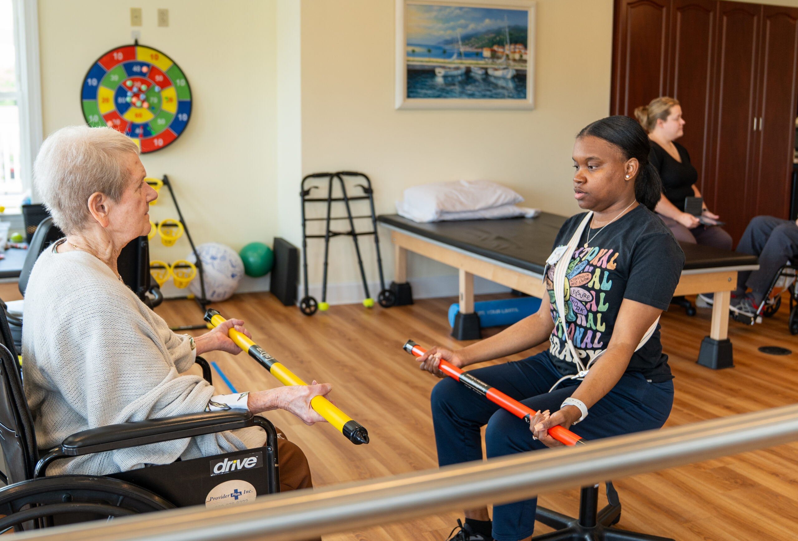 Occupational therapist at Mari de Villa assisting a senior with upper body strength exercises.