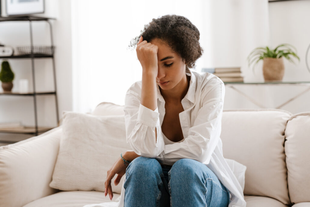 Exhausted woman resting her head on her hand while sitting on a couch, dealing with caregiver stress and burnout