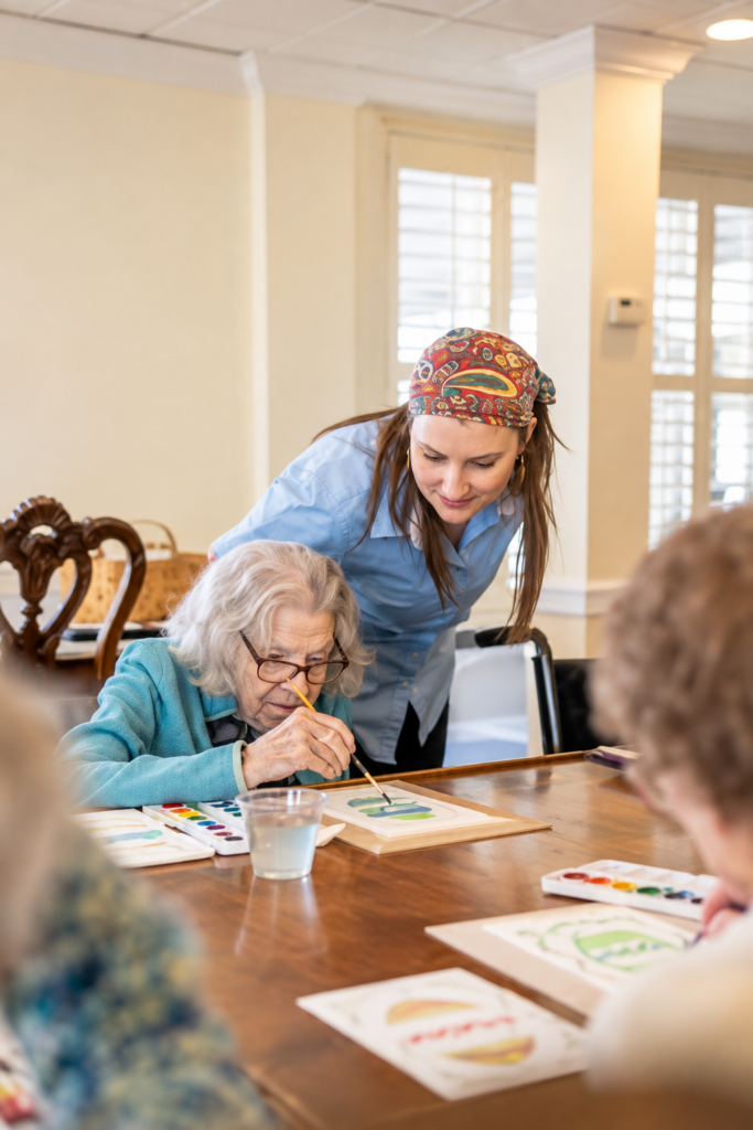 Assisted Living vs. Memory Care: Key Differences St. Louis Families Need to Know 2 Mari de Villa memory care staff member giving a resident one-on-one, hands-on support during an activity